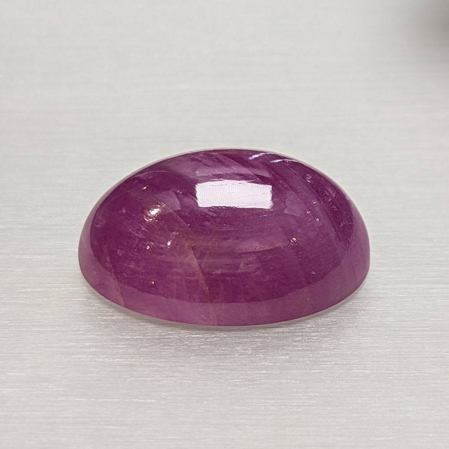 Oval geformter Rubin-Cabochon mit glatter, glänzender Oberfläche auf hellem Untergrund