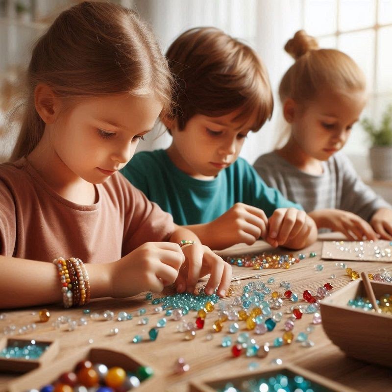 3 Kinder ca. 7 Jahre alt sitzen am Tisch uns basteln mit kleinen bunten Edelsteinen